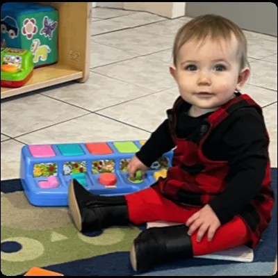 Baby sitting and playing with a toy in the infant room