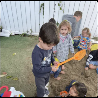 Toddlers digging in the outdoor sandbox