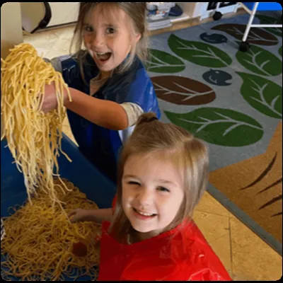 Children laughing during sensory play with noodles