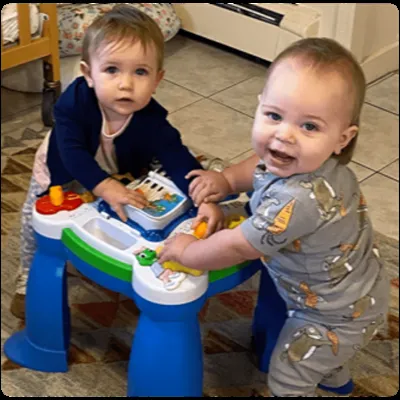 Two smiling babies playing at an activity table at Four Seasons